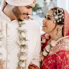 A close-up of the bride and groom sharing a look of pure love and happiness during their wedding ceremony. The details of their stunning wedding attire and jewelry are captured beautifully.