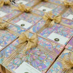 A large batch of our Diwali hampers featuring a unique holographic and pastel mandala design. Each box is tied with a shimmering gold ribbon and a custom tag, ready to deliver festive cheer for a large corporate order.
