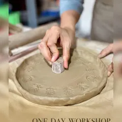 Beyond the wheel, hand-building opens up a world of possibilities. Here, a student uses a simple wooden stamp to add a personal, leafy texture to a plate made using the slab technique.