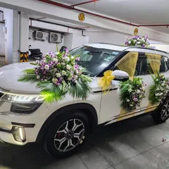 This Kia Seltos is decorated with beautiful bouquets of white roses, purple orchids, and palm leaves. The addition of gold fabric draping on the sides adds a touch of glamour to the wedding car.