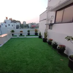 Another view of the terrace, showing how the artificial grass provides a clean, green floor for the entire space, complemented by potted plants along the wall.