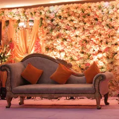 Here is a full view of an indoor engagement stage we designed. A dense wall of peach and cream flowers provides a warm and romantic backdrop, while the vintage-style diwan offers elegant seating for the couple.