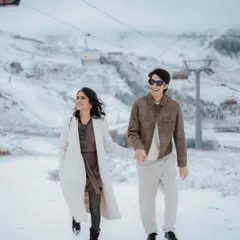Walking hand-in-hand through the snow, with the ski-lifts of Azerbaijan in the background. This image tells a story of adventure and companionship, set against a magnificent mountain landscape.