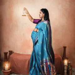 A graceful profile shot in a stunning blue saree. The warm, candle-lit setting with terracotta props complements the richness of traditional Indian textiles.