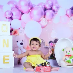 A huge smile from the birthday girl during her cake smash session. The pink and white balloons and teddy bears create a sweet and celebratory backdrop.