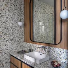 We love the playful yet sophisticated look of terrazzo. In this guest bathroom, we used terrazzo on both the countertop and the wall, pairing it with warm veneer cabinetry for a modern and textural feel.