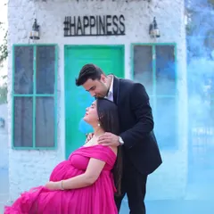 A romantic maternity portrait with blue smoke for a creative gender reveal effect. This session was shot at an outdoor studio location with unique backdrops.
