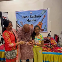 A young student beaming with joy as she is awarded her trophy. These moments of recognition are so important for building a young artist's confidence.