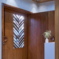 A close-up of a custom-designed wooden door featuring a chevron-patterned glass insert. This detail allows light to pass through while maintaining privacy and adding a touch of modern craftsmanship.