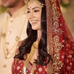 A close-up of a bride's radiant smile, framed by her custom dabka dupatta. The delicate handwork, featuring sitara and tila, was designed to catch the light beautifully.