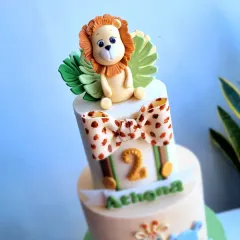 A close-up of the fondant lion topper on the safari cake, surrounded by handcrafted leaves. Each animal figure is made with care to bring a friendly and playful character to the celebration.