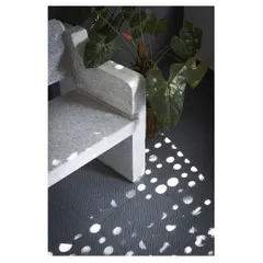 The play of light is a key feature of this home. Here, sunlight passing through a perforated screen creates a beautiful pattern of dots on the floor next to a custom-designed stone bench.