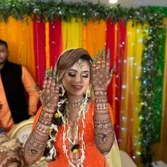 A happy bride showing her back hand mehndi during her ceremony. The design features a mix of net patterns and bold paisley motifs, creating a stunning visual effect.