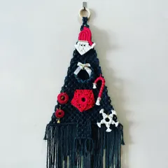 My macrame Christmas tree wall hanging is a unique take on holiday decor. It's adorned with a little Santa, a candy cane, a wreath, and other festive ornaments, all made from macrame.