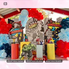 This Avengers party setup is packed with action, featuring a comic-book style "Bang!" backdrop and cutouts of Hulk and Iron Man. The red and blue balloon towers add to the explosive, high-energy feel.