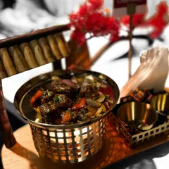 A modern take on a classic Indo-Chinese favorite. Our "Old School Chilli Paneer" is served in a unique basket with a miniature wooden bridge, demonstrating our creative and memorable presentation style.
