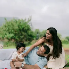 Playful moments like these are what family memories are made of. The whole family engages in a tickle fight on the picnic blanket, their laughter filling the air.