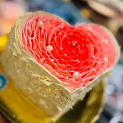 A special heart-shaped cake with a delicate rose petal effect, designed for a wife's birthday. The intricate piping and pearl details create a beautiful and romantic centerpiece for any celebration of love.