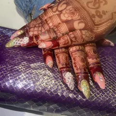 A closer look at our bridal nail art on mehendi-adorned hands. We carefully design each nail to create a cohesive and show-stopping look for your big day.