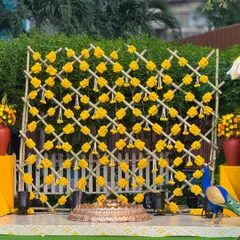 We love the classic sunshine vibe of a Haldi ceremony. Here, a custom bamboo lattice backdrop adorned with bright yellow marigolds and traditional hanging tassels creates a joyful and picture-perfect setting for the celebration.
