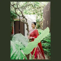 A beautiful bridal portrait, with the bride framed by lush green leaves. This artistic composition adds a touch of nature and artistry to her photo.