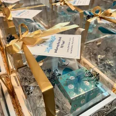 The final presentation of the baby announcement hampers. Each one is packed in a clear box and tied with a luxurious gold ribbon, ready to be gifted to friends and family.