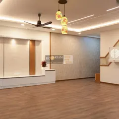 A wide view of a living room in a recently completed 3BHK project. The design features warm wood flooring, a sophisticated TV unit, and a beautifully lit pooja space, all working in harmony.