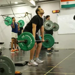 This athlete is in the middle of a heavy pull during a clean. Notice the focus and engagement required to lift a challenging weight from the floor. We ensure our athletes are prepared for these moments.