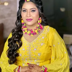 A happy portrait of the Haldi bride, showcasing her complete floral set, including the necklace, earrings, and maang tikka.