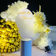 An elegant "Baby in Bloom" baby shower theme, perfect for a modern celebration. This design uses a clean white arched backdrop, a cascade of metallic gold and white balloons, and a stylish dried pampas grass arrangement for a sophisticated look.