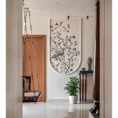 Opposite the dining area, a wall features a traditional peacock wallpaper, creating a beautiful focal point. A small console table holds a Krishna idol, blending spiritual elements with modern decor.