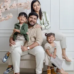 A lovely portrait of a family of four, with smiles all around. The coordinated neutral outfits and soft lighting create a warm and inviting feel.