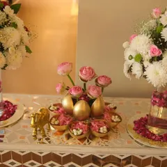 A wider view of the welcome table, showcasing the mirrored mosaic surface that reflects the beautiful floral arrangements and golden accents.