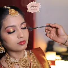 The final touch. Here, I am applying a soft powder to set this bride's Muhurtham makeup. This action shot captures the precision and care I put into creating a look with glowing skin and captivating eyes that feels both special and comfortable.