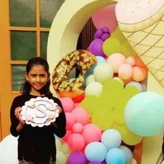A proud moment for the birthday girl! She's holding up her personalized initial plaque against a sweet Candyland-themed backdrop. We love creating custom art projects that make the guest of honor feel extra special.