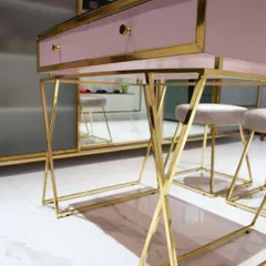 A detail shot of a custom work desk I designed for a retail store. The combination of a dusty pink top, a gold lacquered brass frame with a criss-cross leg design, and a glass surface creates a very chic and glamorous look.