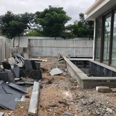 A construction site with piles of stone and rubble. This image is part of the "before" story, showing the raw materials and challenges that are overcome to create a polished, serene garden.