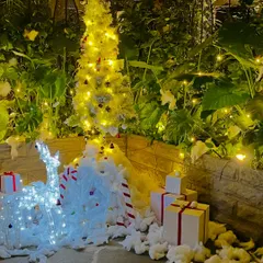 An enchanting outdoor Christmas installation perfect for a corporate building entrance or garden. This setup includes a beautifully lit white Christmas tree, glowing reindeer figures, faux snow, and neatly wrapped gift box props, creating a magical winter wonderland scene.