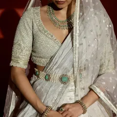 A detailed view of the couture craftsmanship, this shot highlights the exquisite hand-embroidery on the bridal blouse. The precise pearl work, sweetheart neckline, and the unique emerald-studded belt demonstrate the level of artistry that goes into each bespoke creation.