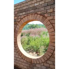A simple circular window, perfectly framed with brick, offers a curated view of the wildflowers outside. This detail demonstrates how even the smallest opening can be designed to create a powerful connection with the landscape.