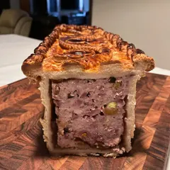 A cross-section of the Pâté En Croute, revealing the mosaic of lamb, poultry, and pork, studded with Armagnac-soaked prunes and apricots.