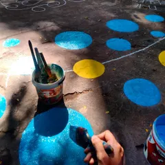 A close-up of me painting the bright blue and yellow circles for the floor mural. Every shape is part of an interactive game designed to get kids moving.