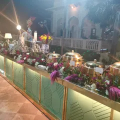 A lavish buffet display for a destination wedding at the Laxmi Vilas Palace. The setup is adorned with rich, colourful flowers and traditional brass serving dishes, reflecting the regal setting of the event.