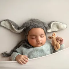 Even simple props can be so effective. Here, a cozy bunny hat adds a touch of whimsy to this portrait of a sleeping twin, showing how accessories can enhance a newborn photo.