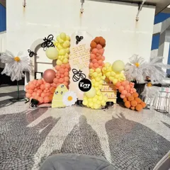 A look at our "Sweet as Can Bee" theme in action on a sunny rooftop. This setup features a vibrant balloon garland in shades of yellow and peach, oversized daisies, and adorable bee accents for a cheerful and playful baby shower celebration.