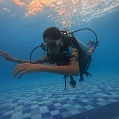 A student glides effortlessly underwater, practicing buoyancy control during a scuba session at our Malpe summer camp.