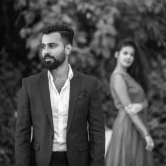 A classic black and white portrait that emphasizes emotion. The focus on the groom with the bride softly in the background creates a thoughtful and artistic composition.