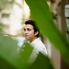 A handsome portrait of the groom, framed by lush green leaves. The natural setting and his thoughtful expression create a serene and stylish image.