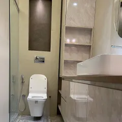 This bathroom combines a floating vanity with a marble-like finish and beautiful patterned floor tiles. A tall, lit niche next to the toilet provides space for decor or toiletries.
