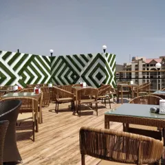 The rooftop area at Gilly's, featuring an artificial green wall with a geometric pattern, wicker furniture, and an open-air feel.